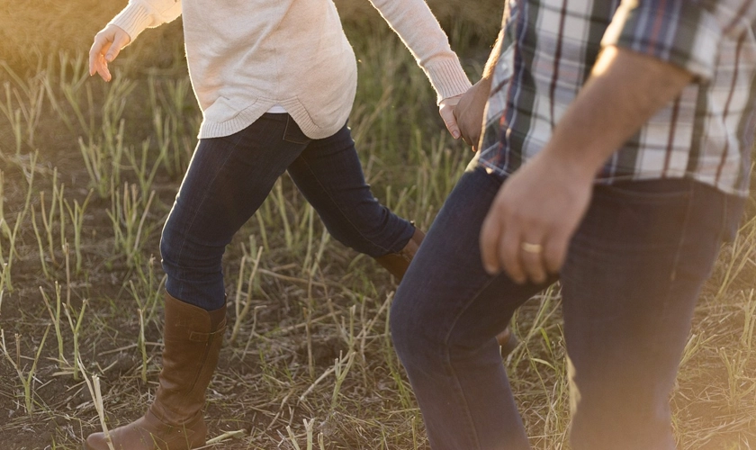 Man walking through a field with his wife.